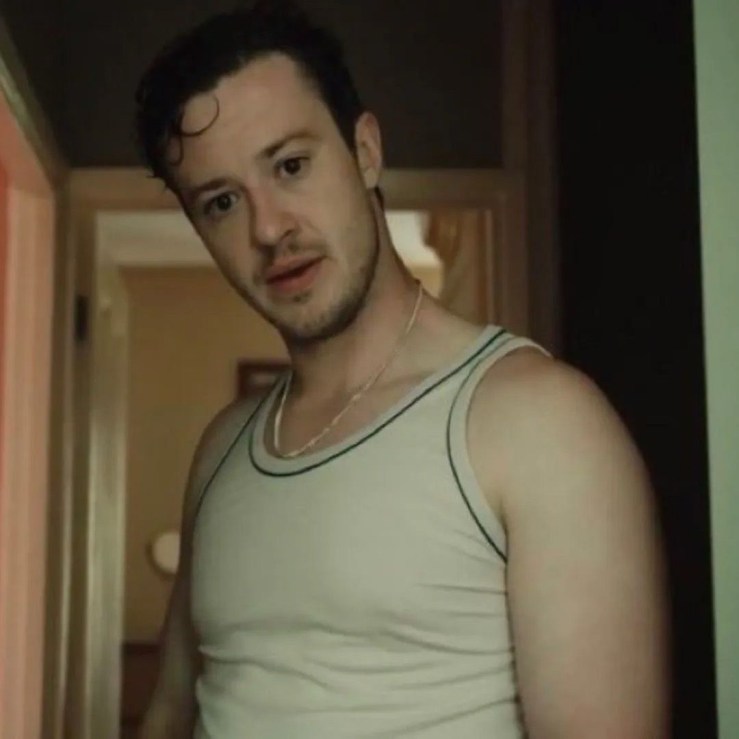 Michael is wearing a white vest and played by Joseph Quinn